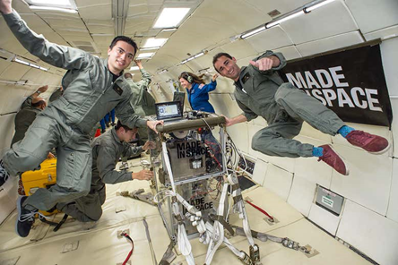 People in flight suits float in a zero-gravity environment inside an aircraft, with scientific equipment labeled MADE IN SPACE visible in the center and a banner on the wall—demonstrating cutting-edge Colorado engineering in action.