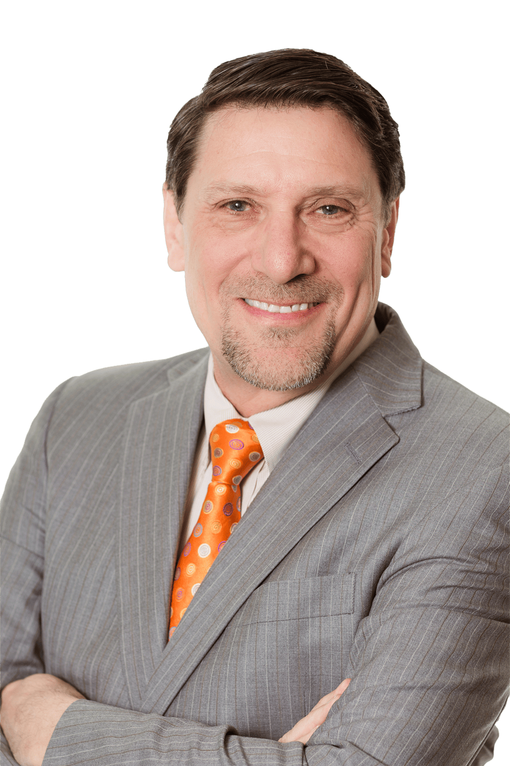 A smiling man in a gray pinstripe suit with an orange polka dot tie, standing with his arms crossed, represents a professional in SDVOSB engineering against a plain, transparent background.