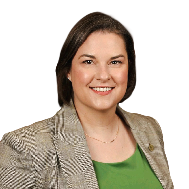 A woman with short brown hair, wearing a gray plaid blazer over a green top and delicate necklace, smiles at the camera against a plain background—representing the confidence of a leading Denver engineer in structural design.