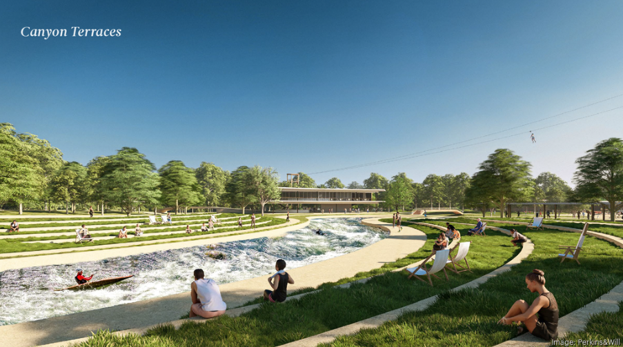 People relax on grassy terraces beside a winding stream under a clear blue sky; some sit on benches, others lounge on the grass, and a kayaker paddles in the water, with modern buildings and trees in the background.